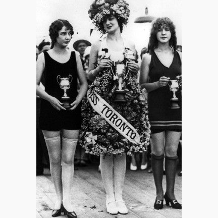 Miss Toronto in a dress made of flowers  flanked by two runners up in swim-suits, all holding trophies 1926.